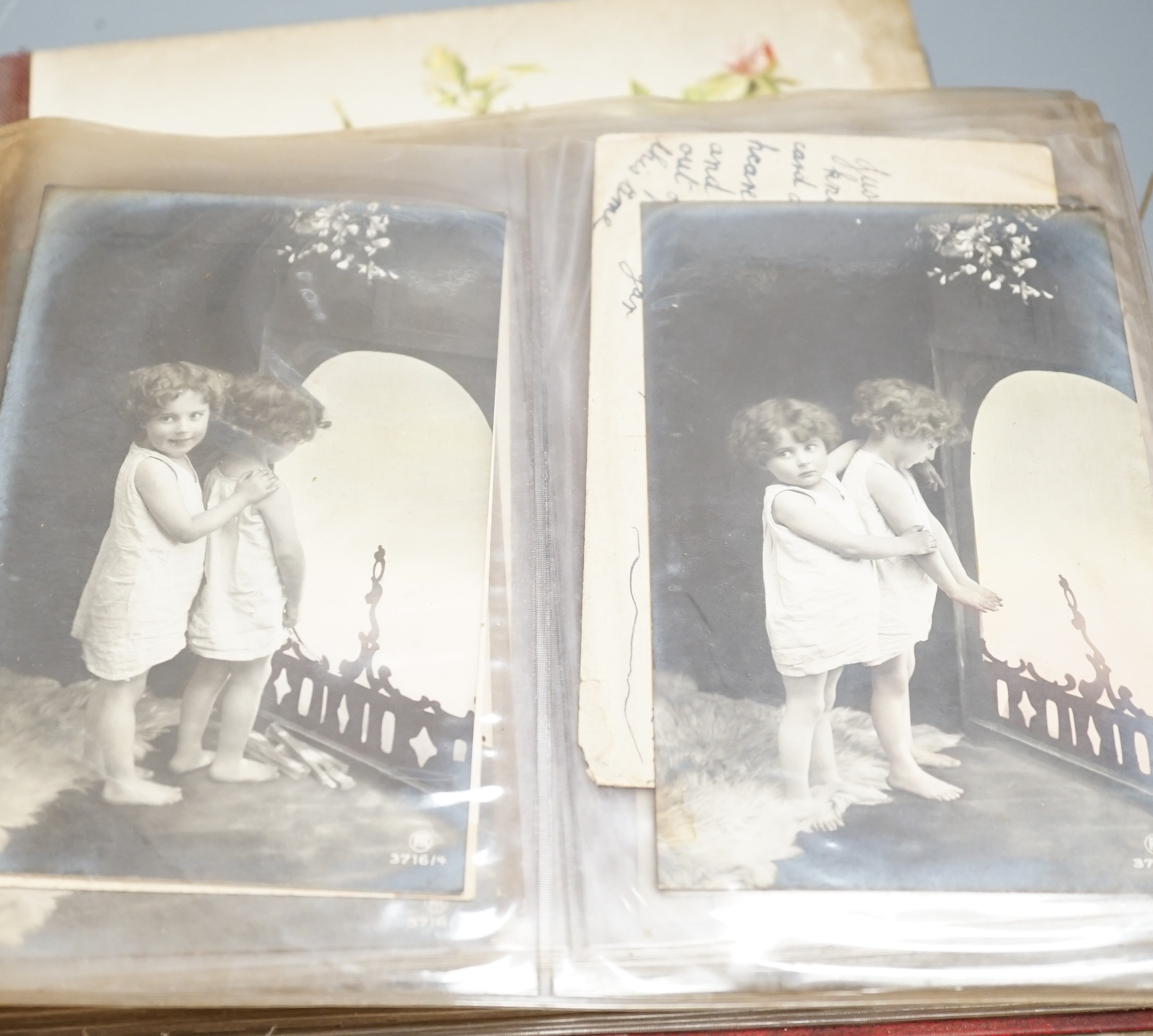 An early 20th century postcard collection in two albums and an empty late Victorian leather photo album